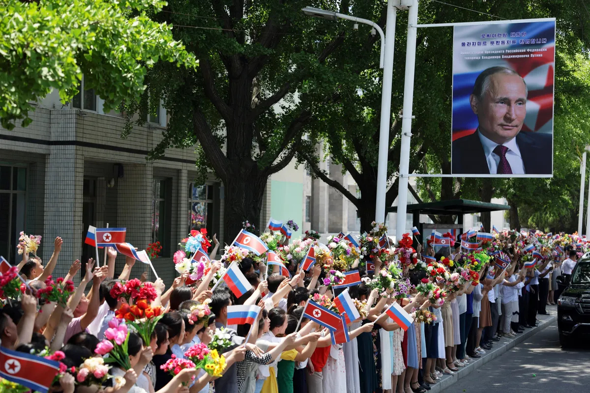 Crowds line the streets waving Russian and North Korean flags as Putin and Kim’s motorcade passes through Pyongyang. Photo: EPA-EFE / GAVRIIL GRIGOROV / SPUTNIK / KREMLIN POOL 