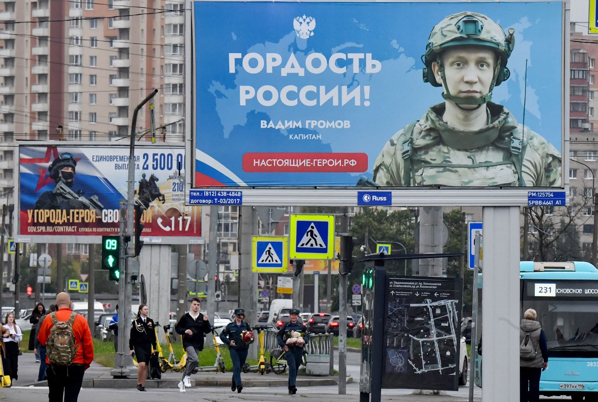 Кадеты с цветами бегут мимо пропагандистских билбордов в День знаний в Санкт-Петербурге, 1 сентября 2025 года. Фото: Ольга Мальцева / AFP / Scanpix / LETA